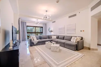 a living room with a couch and a tv at Stylish 2 bedroom apartment with Maid Room I Fairmont South Residence I Palm Jumeirah in Dubai
