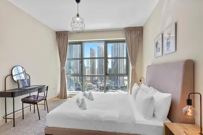 a bedroom with a bed and a desk and a large window at Upscale 1 bedroom in the heart of Downtown in Dubai