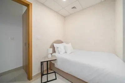 a white bedroom with a bed and a table with a lamp at Bellevue Towers by Luxe Living - Full Burj Khalifa View in Dubai