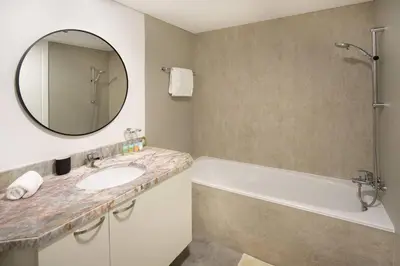 a bathroom with a tub and a sink and a mirror at Prime Retreats - steps to Grosvenor Hotel Marina in Dubai