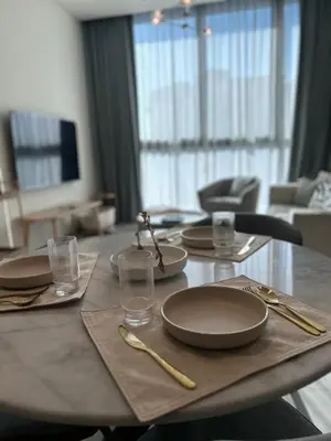 a table with plates and utensils on top of it at Premium 1BHK Apt In Signature living, JVC! Pool view in Dubai