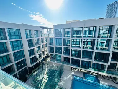 a large building with a swimming pool in front of it at Premium 1BHK Apt In Signature living, JVC! Pool view in Dubai