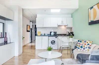 a living room and kitchen with a couch and a table at Luxe Studio with Upgraded Interior in Sports City in Dubai
