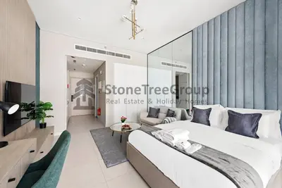 a bedroom with a large bed and a living room at Luxury Studio Near To Metro in Dubai