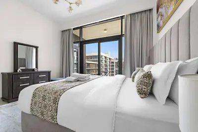 a white bedroom with a large bed and a window at Modern 1 Br Near To Park in Dubai