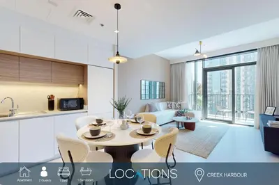 a kitchen and living room with a table and chairs at Creek Edge - One Bedroom with Partial Sea View in Dubai