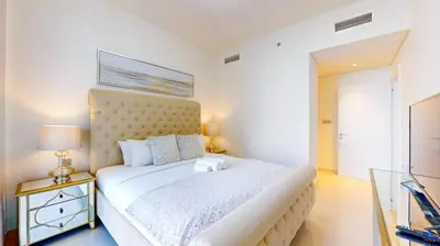 a bedroom with a large white bed and a night stand at Beach Vista 2 - Two Bedroom with Partial Sea View in Dubai