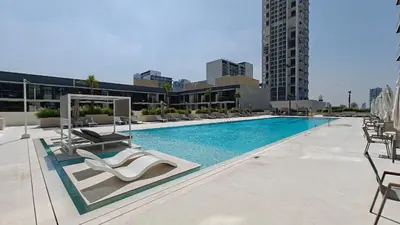 a swimming pool with lounge chairs and a building at Luxurious 1-Bedroom Oasis l Binghatti Corner, JVC in Dubai