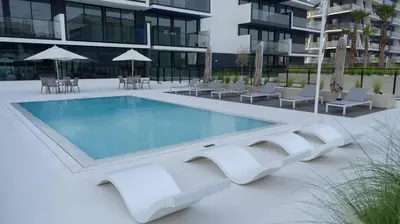 a swimming pool in front of a building at Stylish 1br Apt Jvc W Pool & Free Parking in Dubai