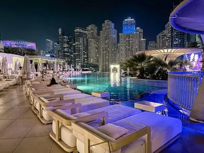 a pool with lounge chairs and a city skyline at night at Splendid Cozy Studio - Address Dubai Marina in Dubai