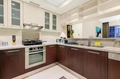 a kitchen with wooden cabinets and a sink at Chic City Apartment in Dubai Gym, Pool, and Free Parking in Dubai