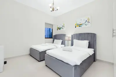 a bedroom with two beds and a chandelier at 4BR Jumeirah Beach Stay with Dubai Eye Views & Near Marina Walk in Dubai