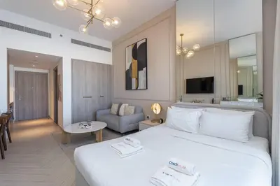 a bedroom with a large white bed and a living room at Beautiful Pool View JVC Cozy and Stylish Czechin in Dubai