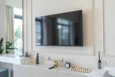 a living room with a tv on a wall at Beautiful Pool View JVC Cozy and Stylish Czechin in Dubai