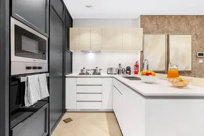 a kitchen with white cabinets and a black refrigerator at FIRST CLASS 2BR Serene Retreat in Wilton in Dubai