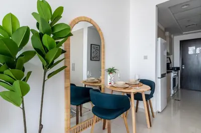 a dining room with a table and blue chairs and a mirror at GuestReady - Elegant retreat at Damac Hills in Dubai