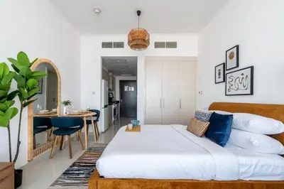 a bedroom with a large bed and a kitchen at GuestReady - Elegant retreat at Damac Hills in Dubai