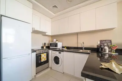 a kitchen with white cabinets and a washer and dryer at Frank Porter - DAMAC Tower 108 - 1BR in Dubai