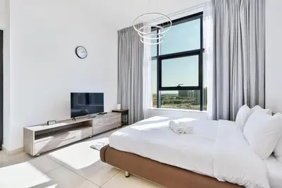 a bedroom with a bed and a tv and a window at Lovely Studio with Pool and Gym in Dubai