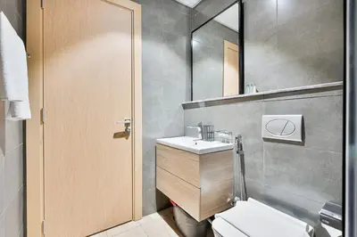 a bathroom with a toilet and a sink and a mirror at Lovely Studio with Pool and Gym in Dubai
