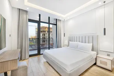 a bedroom with a bed and a desk and a window at Daniels 1BR at Jumeirah Garden City in Dubai