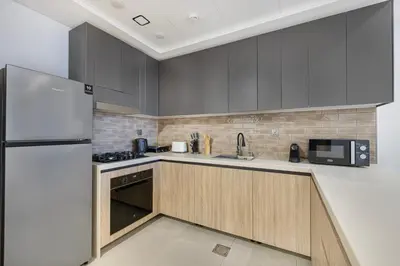 a kitchen with gray cabinets and a refrigerator at Daniels 1BR at Jumeirah Garden City in Dubai