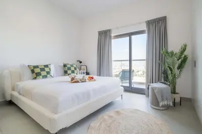 a white bedroom with a large bed and a large window at Frank Porter - Bella Rose in Dubai