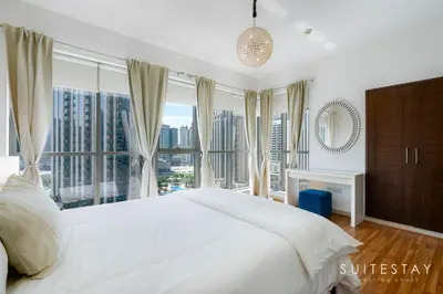 a bedroom with a white bed and large windows at One Bed with Burj Khalifa View in Dubai
