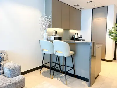 a kitchen with two white stools at a counter at Chic 1-Bedroom with Epic Burj Khalifa Views in Dubai