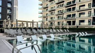 a swimming pool with lounge chairs and a building at Chic 1-Bedroom with Epic Burj Khalifa Views in Dubai