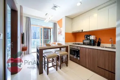 a kitchen with an island with stools and a table at 1BR With Burj Khalifa View and Accomodates 4 People in Dubai