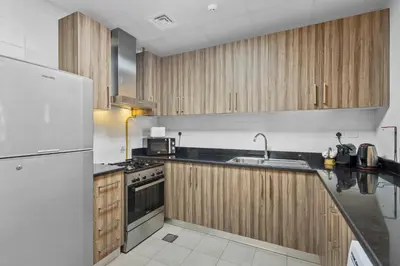 a kitchen with wooden cabinets and a white refrigerator at Premium 1 bedroom Apartment near Dubai Mall in Dubai