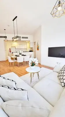 a living room with a white couch and a table at Luxury 2BR Carson Tower B Apt in Dubai