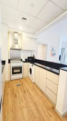 a kitchen with white cabinets and a wooden floor at Luxury 2BR Carson Tower B Apt in Dubai