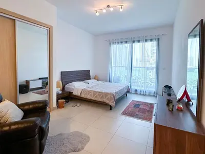 a bedroom with a bed and a large window at Cozy Studio in JVC in Dubai