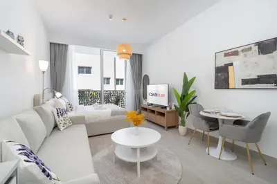 a white living room with a couch and a table at Bright & Airy Studio in JVC in Dubai
