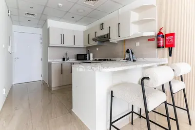a kitchen with white cabinets and bar stools at Newly Furnished Unit in Elite, Business Bay in Dubai