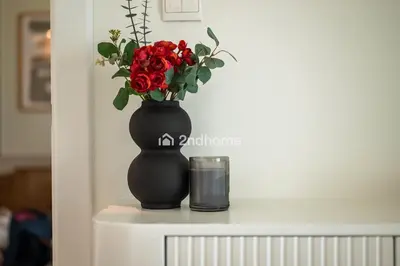 a black vase with red roses in it on a table at Newly Furnished Unit in Elite, Business Bay in Dubai