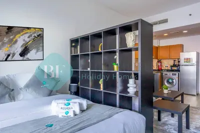 a bedroom with a bed and a kitchen with a refrigerator at Bloomfields Stu Lago With Vista Sea View in Dubai