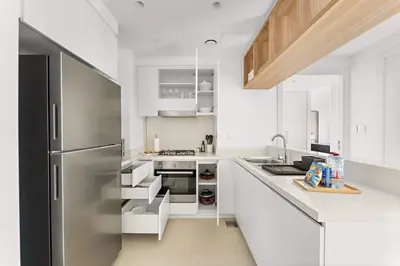 a kitchen with white cabinets and a stainless steel refrigerator at Silkhaus Full Burj Khalifa Views in Downtown in Dubai