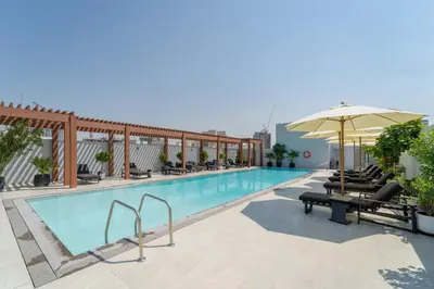 a pool at a hotel with chairs and an umbrella at Art of Modern Illumination in Dubai