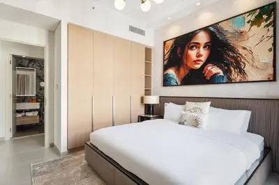 a bedroom with a large white bed and a painting on the wall at Dubai Creek Poolside view Apartment - By DuStay in Dubai