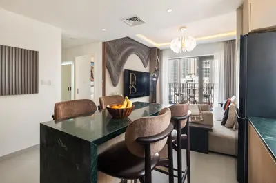 a kitchen and living room with a table and chairs at Dubai Creek Poolside view Apartment - By DuStay in Dubai