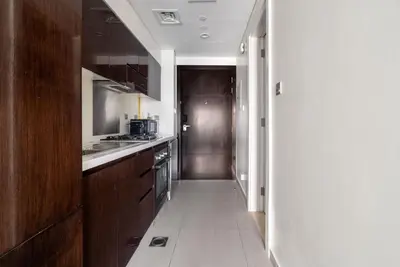 a small kitchen with wooden cabinets and a hallway at GuestReady - Luxurious studio in Business Bay in Dubai