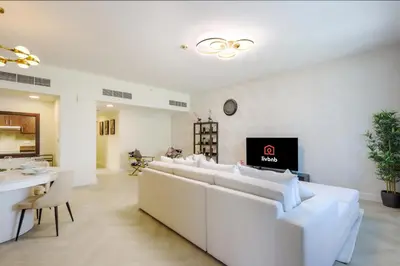a living room with white couches and a tv at Livbnb Suites - Burj Khalifa View 2BR spacious apt in Dubai