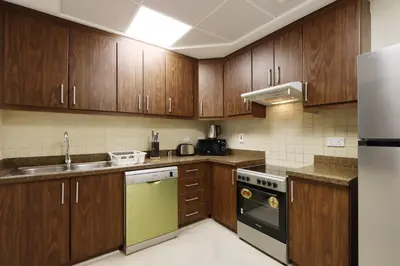 a kitchen with wooden cabinets and a sink and a refrigerator at Livbnb Suites - Burj Khalifa View 2BR spacious apt in Dubai