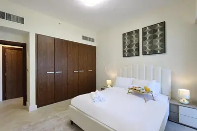 a bedroom with a large white bed and wooden cabinets at Livbnb Suites - Burj Khalifa View 2BR spacious apt in Dubai