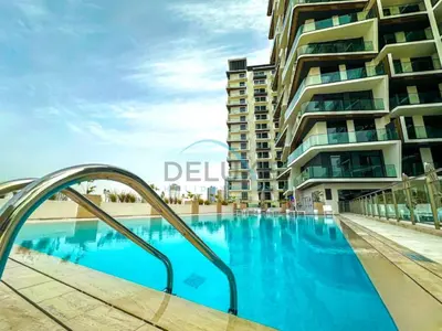 a swimming pool in front of a tall building at Modern 1BR Apartment in Binghatti Luna, Jumeirah Village Circle by Deluxe Holiday Homes in Dubai