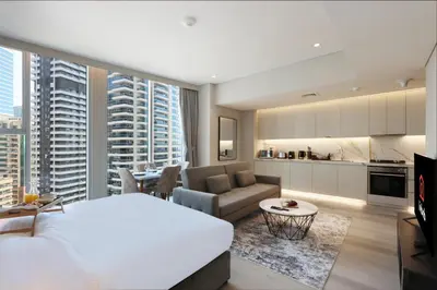 a bedroom with a large white bed and a living room at Livbnb -Glam Studio in Marina Next to Marina Walk in Dubai