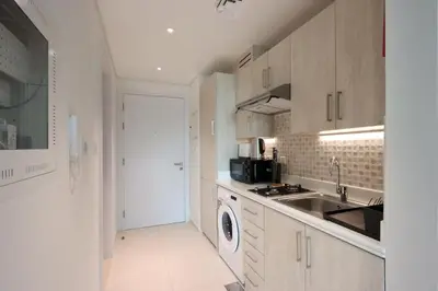 a white kitchen with a sink and a dishwasher at Exquisite Studio near Nakheel Mall by Livbnb in Dubai